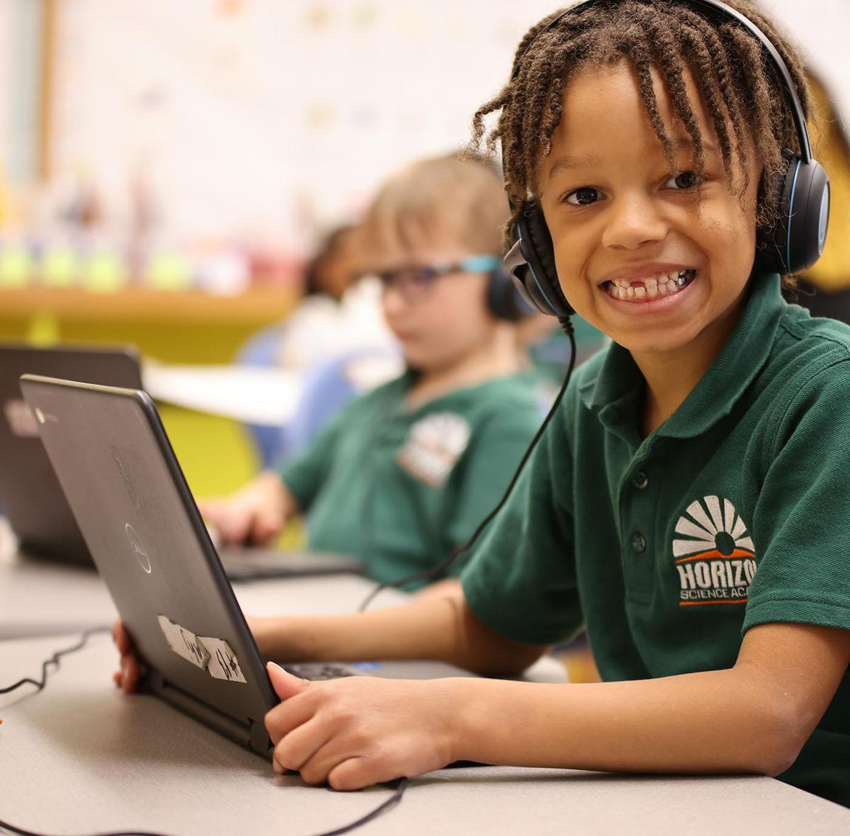 HSA Cedar Rapids student wearing headphones uses a laptop in class