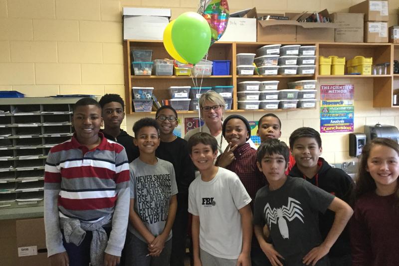 A photo of the 2018-2019 teacher of the year Mrs. Adams. She is holding balloons and surrounded by some 5th grade students after receiving the news that she won Teacher of the Year.