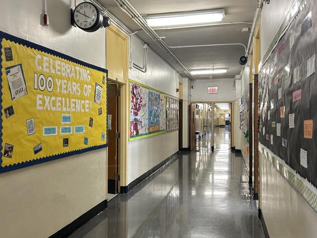 A school hallway decorated with colorful bulletin boards and a clock on the wall.
