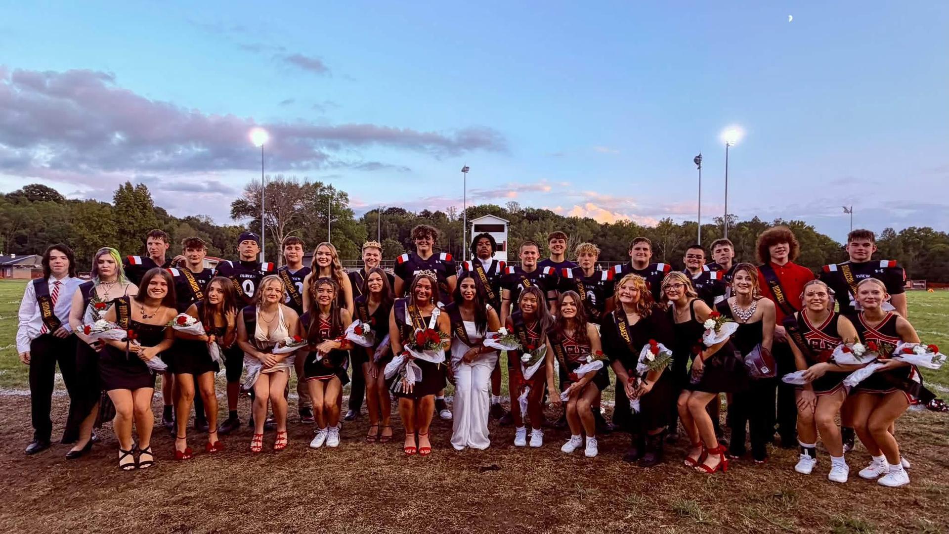 A large group of people in formal attire celebrating on a sports field.