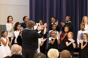 5th graders clap and smile while singing in a choir