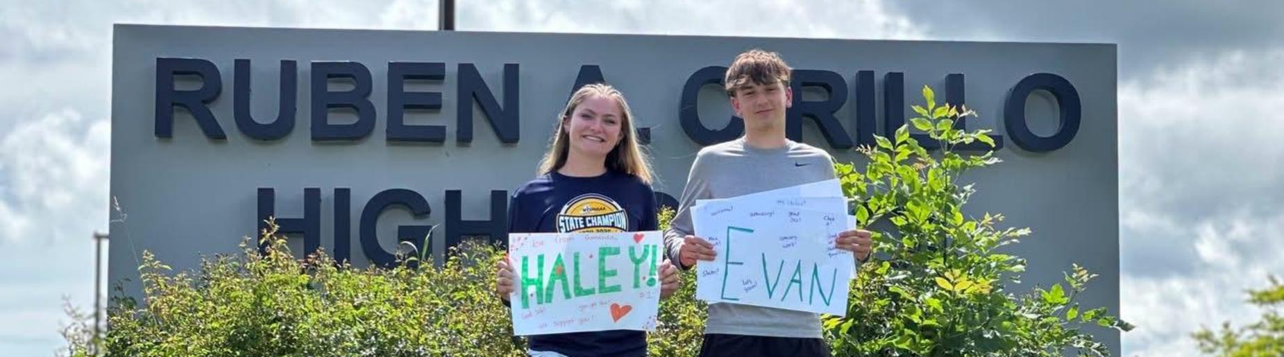 two track students in front of our HS sign