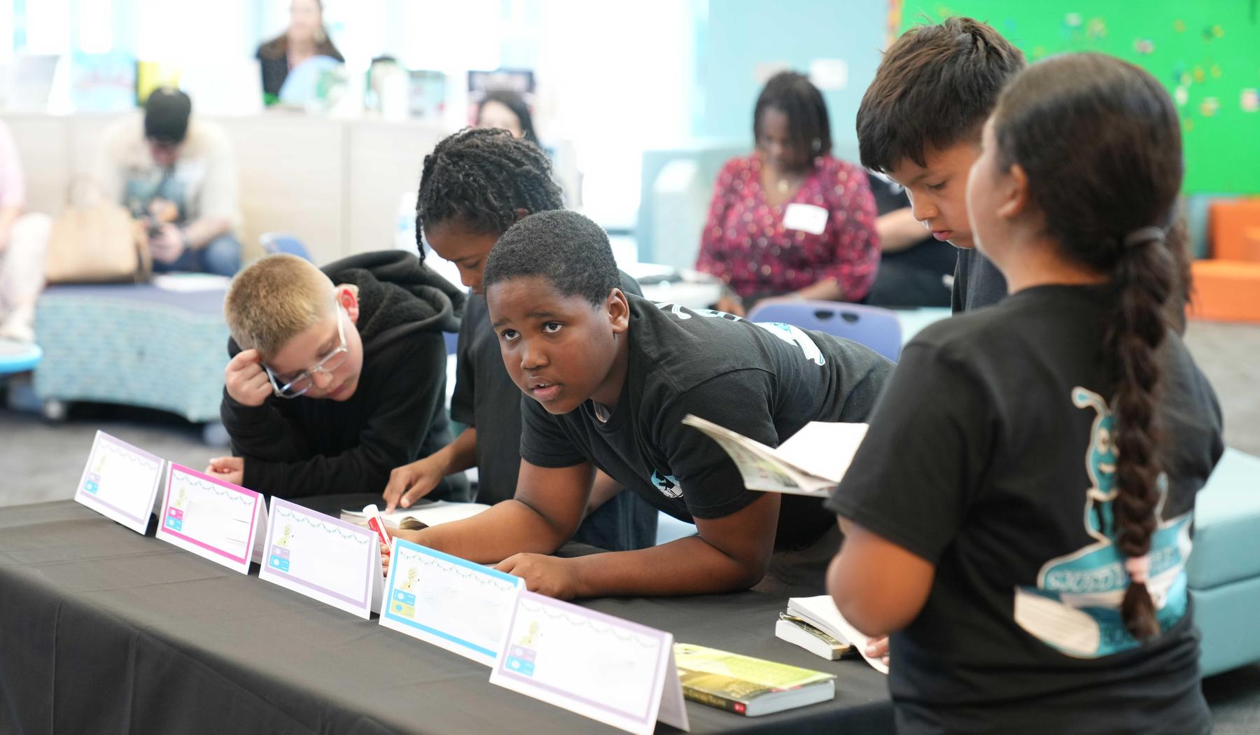 A group of children engaged in a reading activity at a table.