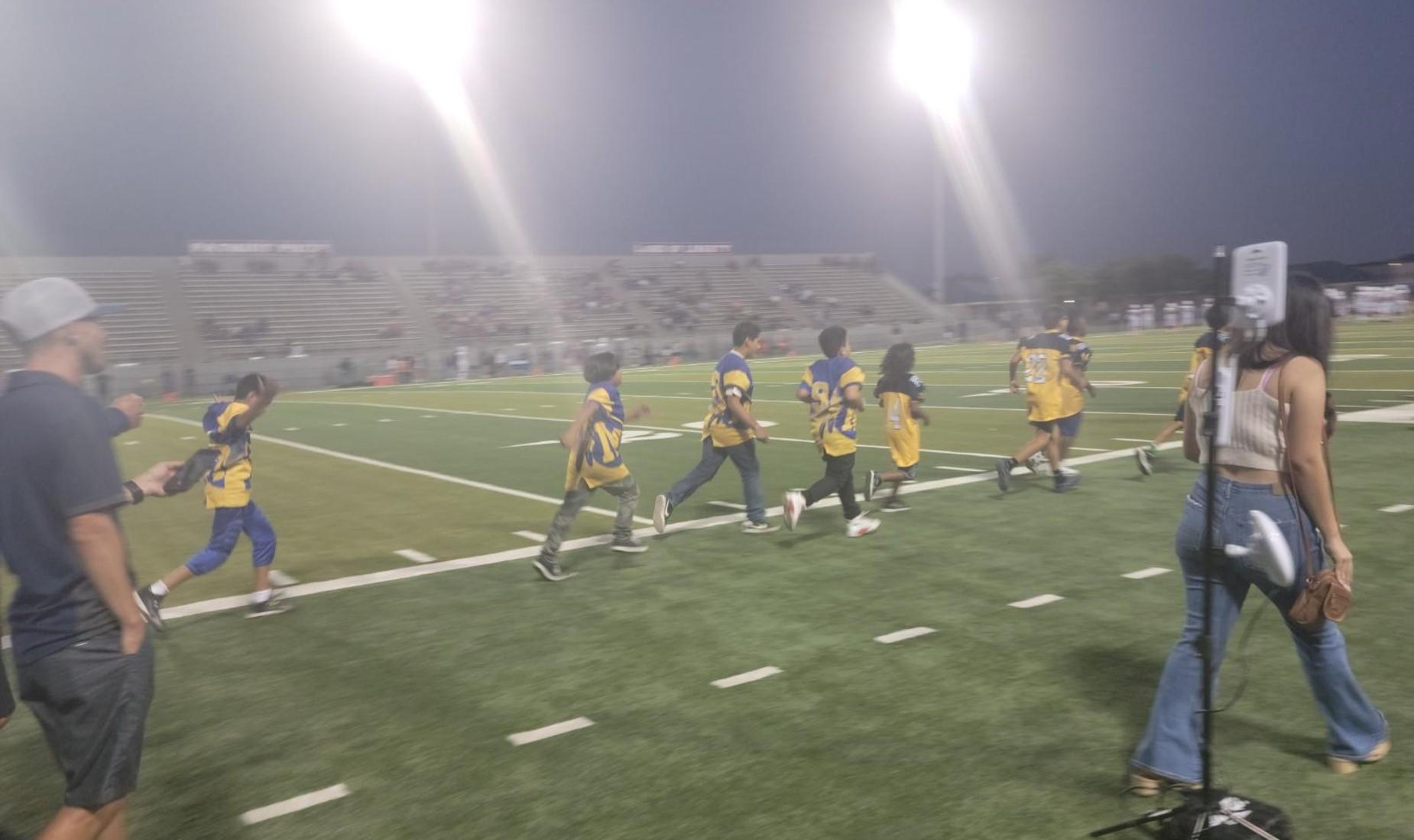 Football players running on the field during Elementary Spirit Night