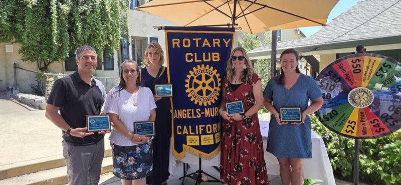 one man and four woman teachers holding plaques