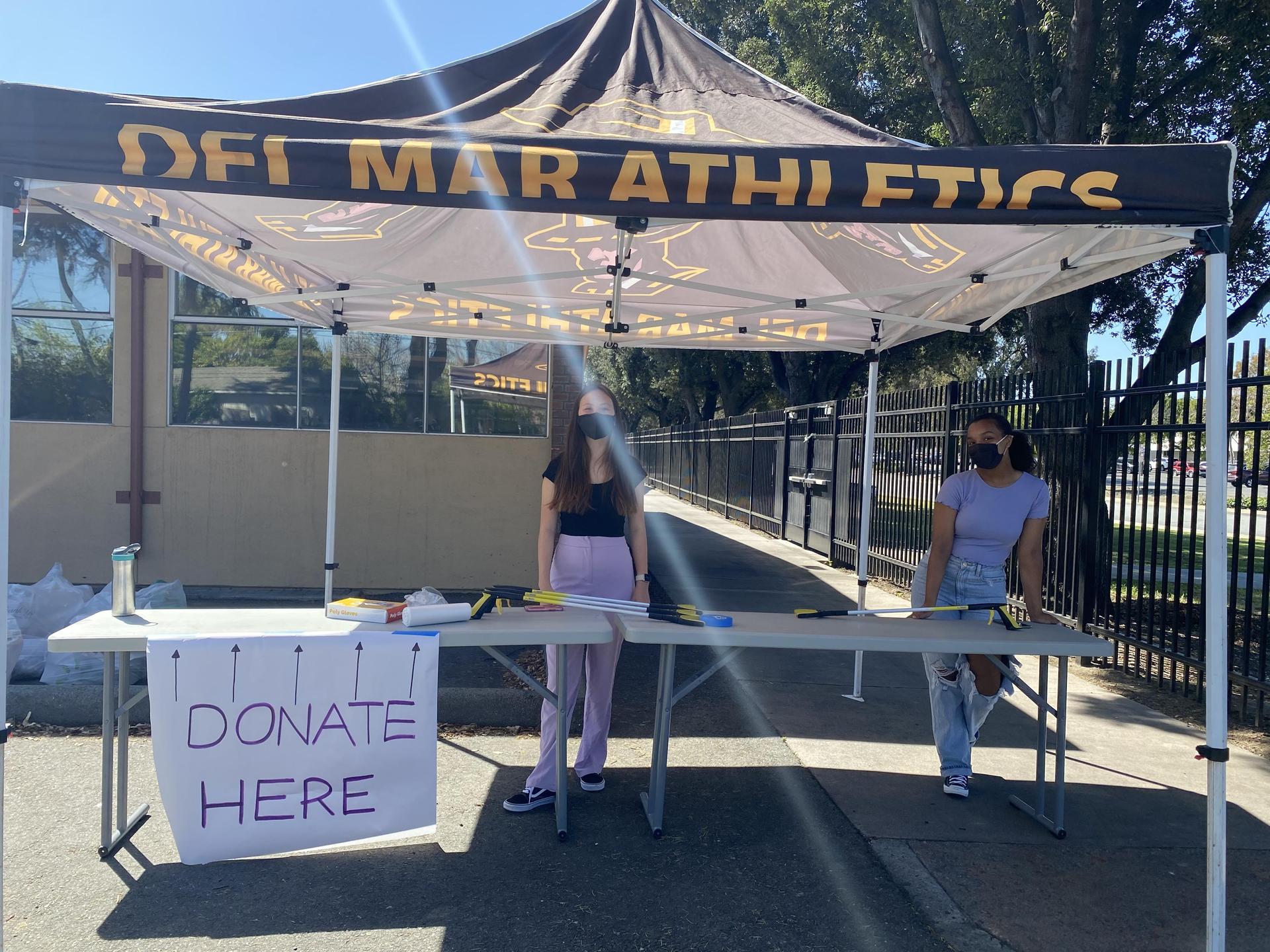 students at table accepting items during women's month donation drive