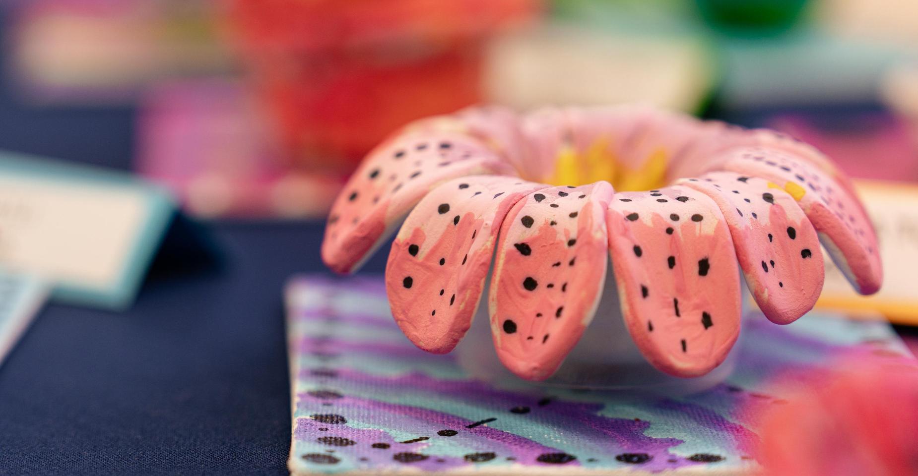 Colorful pink flower sculpture with spotted petals on a patterned background.