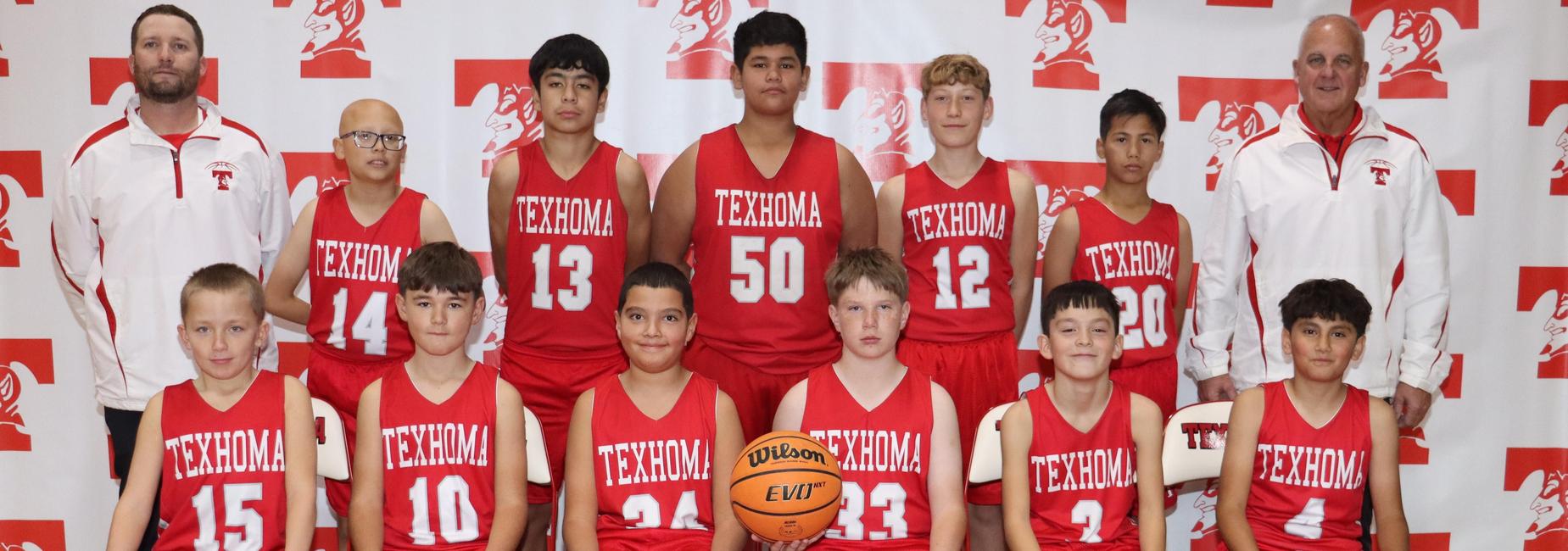 Boys basketball team posing for a group photo with jerseys and a basketball.