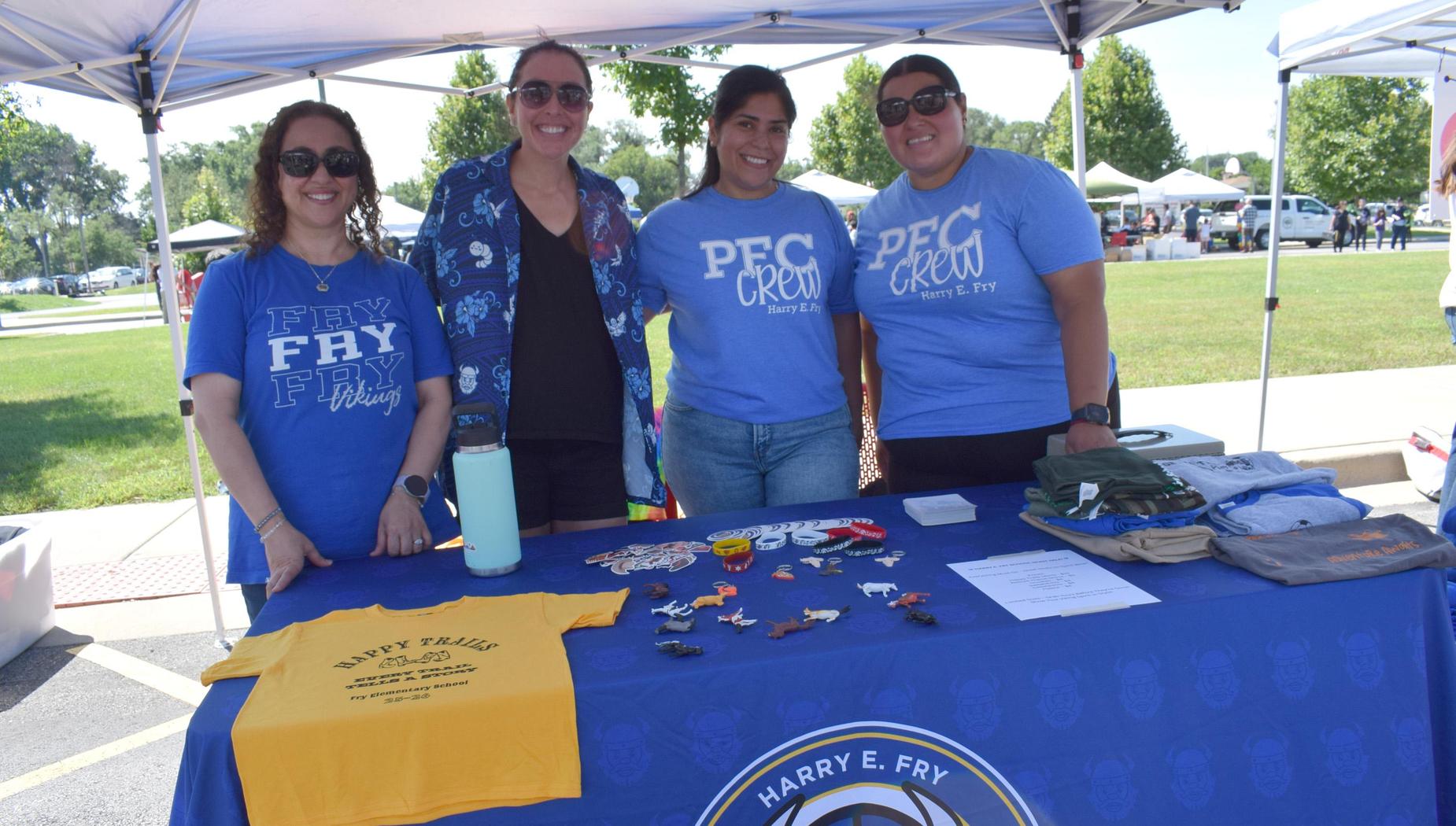 Team members in blue shirts promoting an event with various items on a table.