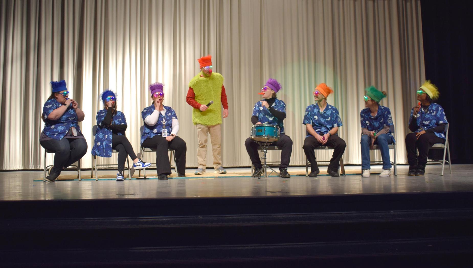 A colorful performance with costumed cast members on stage.
