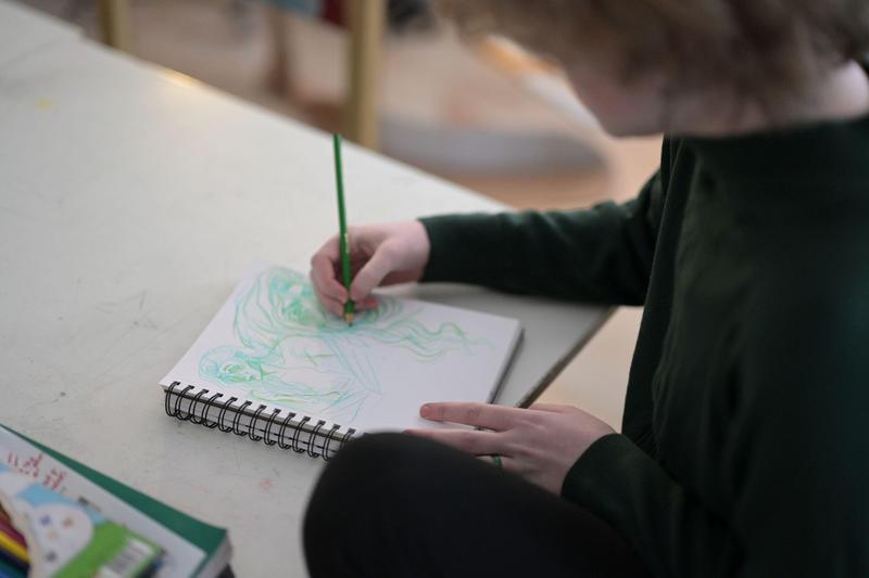 student at tuition-free public charter school HCIS drawing with a green pencil in a sketchbook