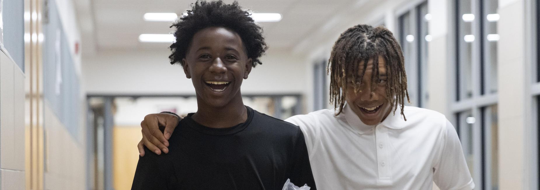 Two Dickson students smile and laugh as they walk down the hall