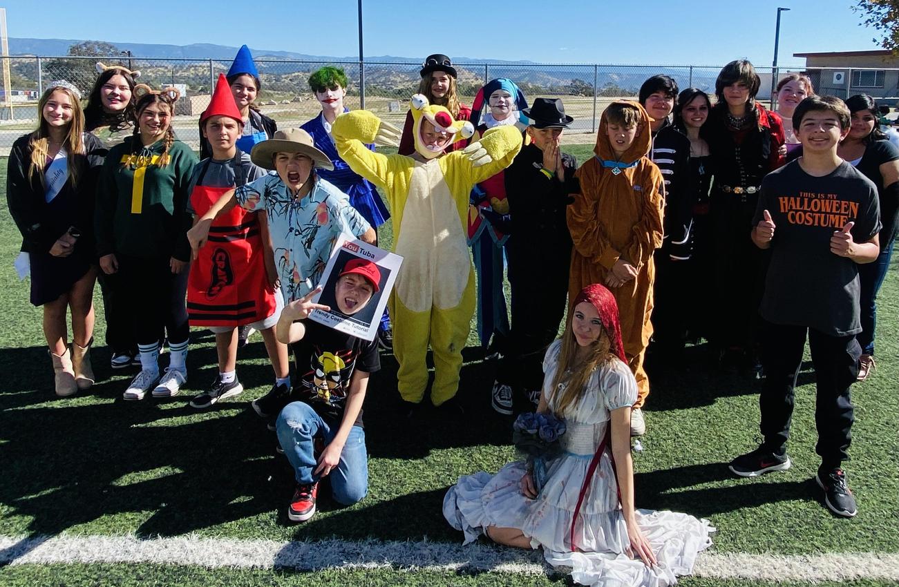 Group of people in costumes celebrating Halloween in a sunny outdoor setting.
