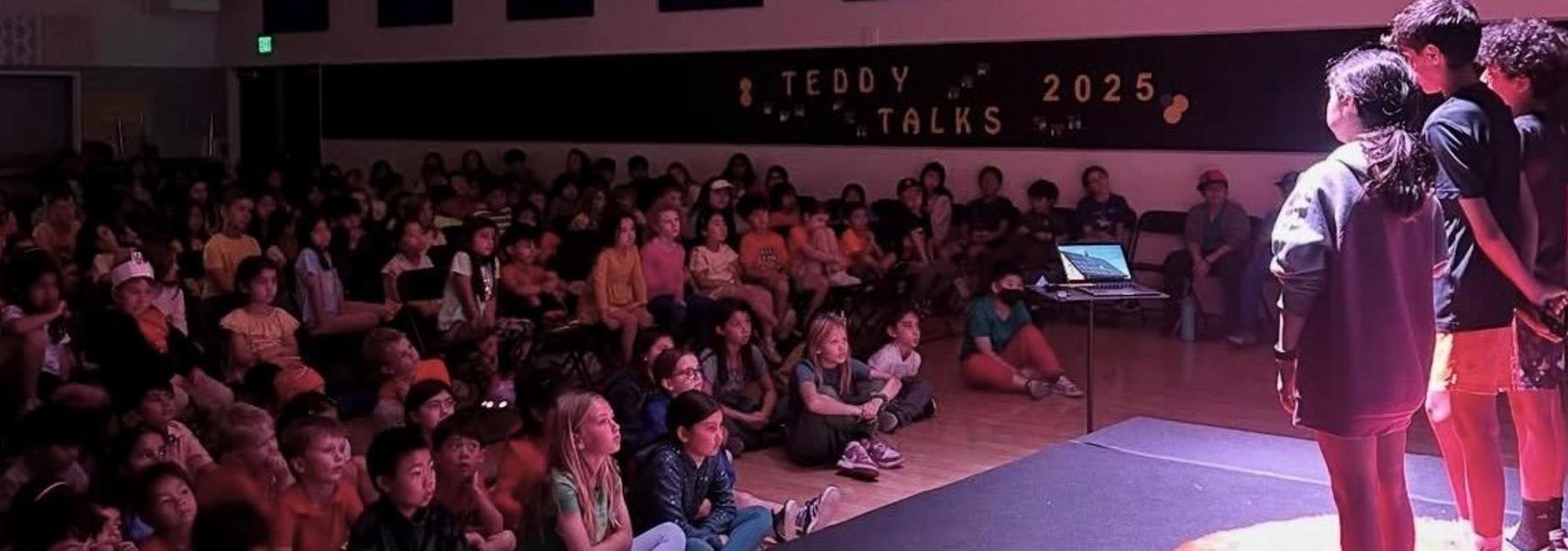 A group of Roosevelt students presenting their Teddy Talks on stage to an audience sitting in the dark.