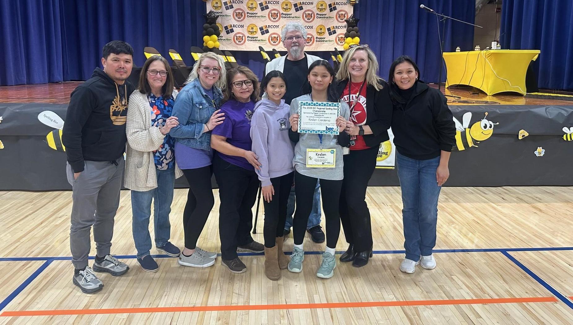 Group of people celebrating with a certificate on a stage decorated with bees.