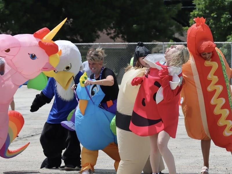 People in colorful inflatable costumes gather and play together outdoors.