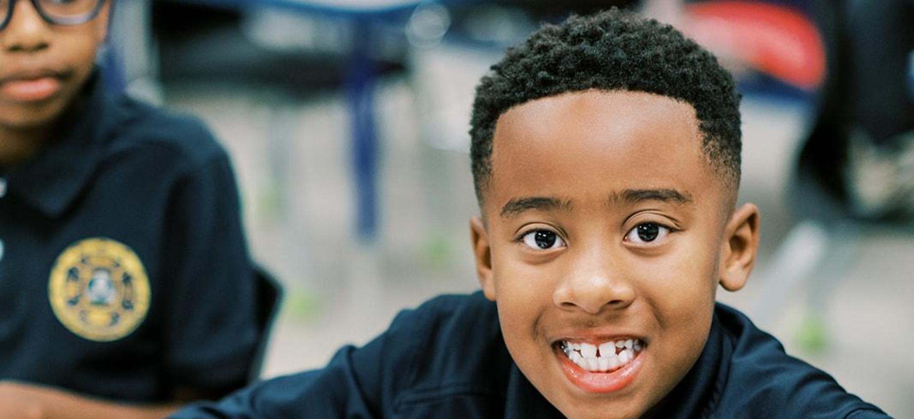 Smiling elementary student colors at his desk