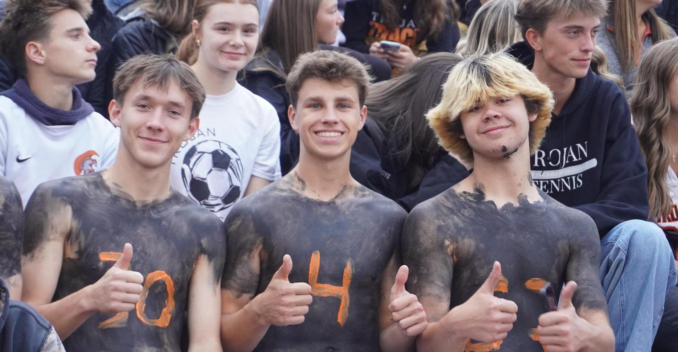 Three students painted their torsos with black paint and orange numbers for their TK Trojan football player classmates.