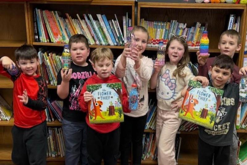 6 students hold books and wildflowers that they planted