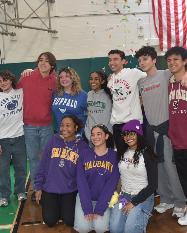 Students pose in shirts saying where they will attend college