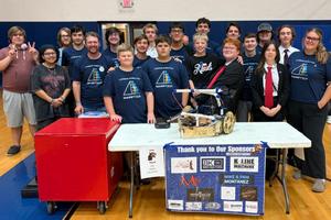 Group of students standing behind a table with a robot on it