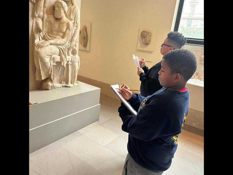 Students complete fieldwork journals in front of a museum exhibit