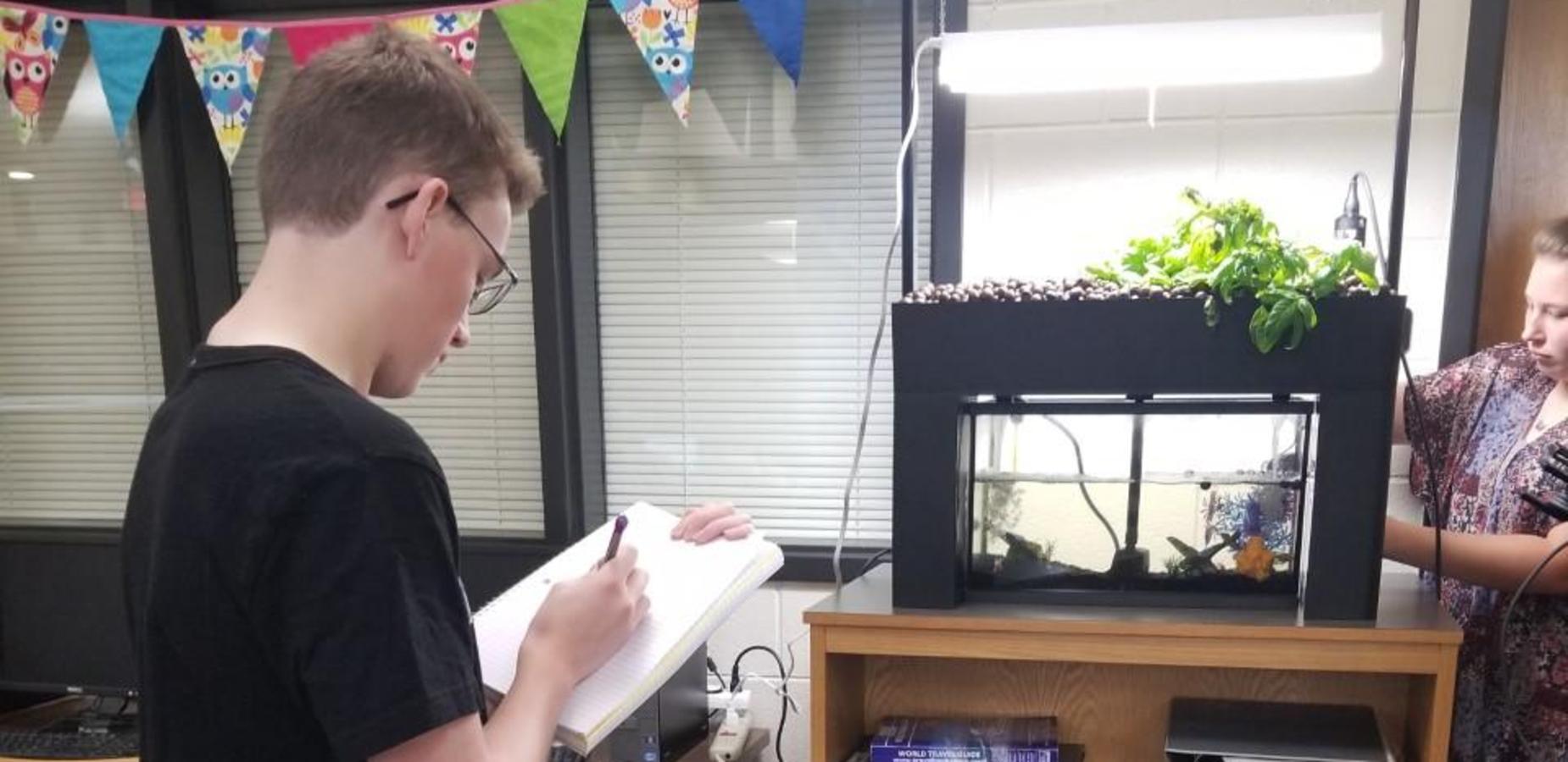 Students collecting data from aquaponics fish tank in the library.