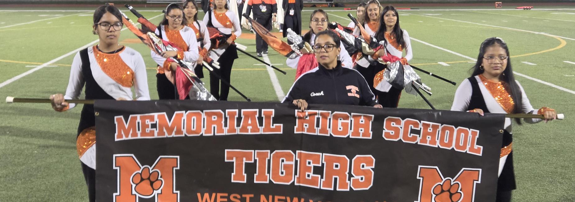 Marching band members holding a banner for Memorial High School Tigers.