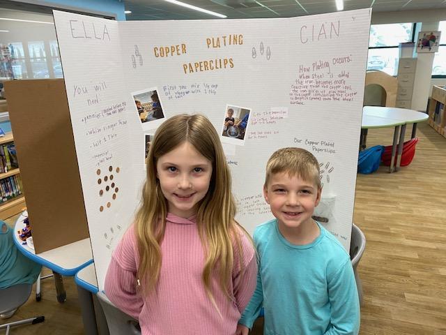 Photo of two student smiling in front of their poster presentation