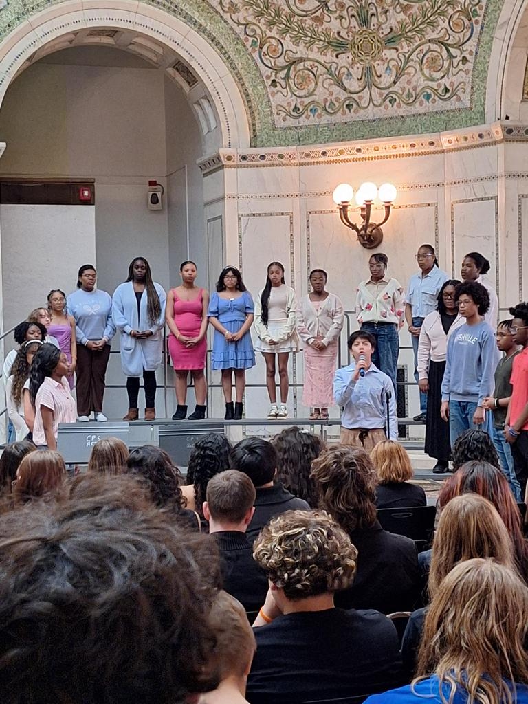 Choir singing in front of seated crowd.