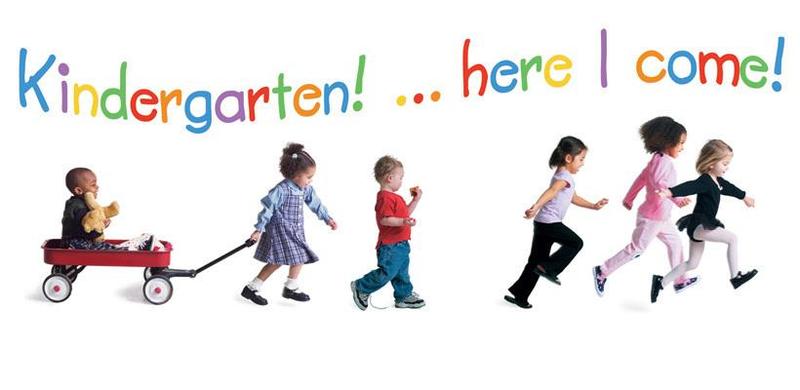 5 kindergartners walking in line. 1 of them is being pulled in a wagon.
