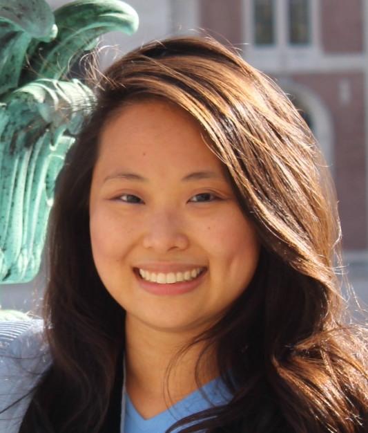 Smiling woman with long hair standing in front of a green sculpture.