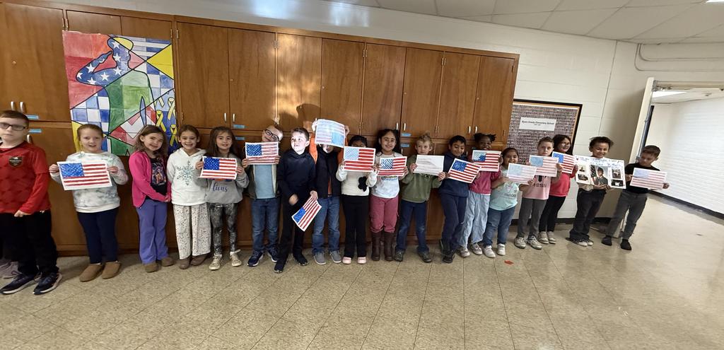 Students hold hand painted American flags in a hall way