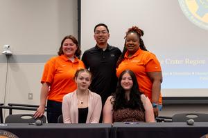 Two students smile with representatives from Super Radiator Coils during CTE Signing Day
