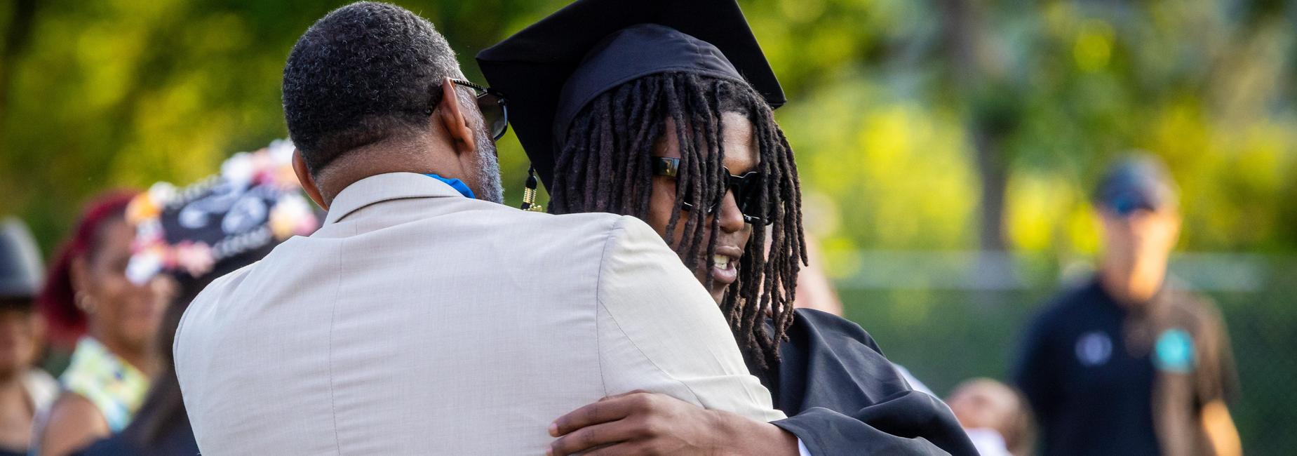 A graduate hugs Mr. Brown before receiving diploma