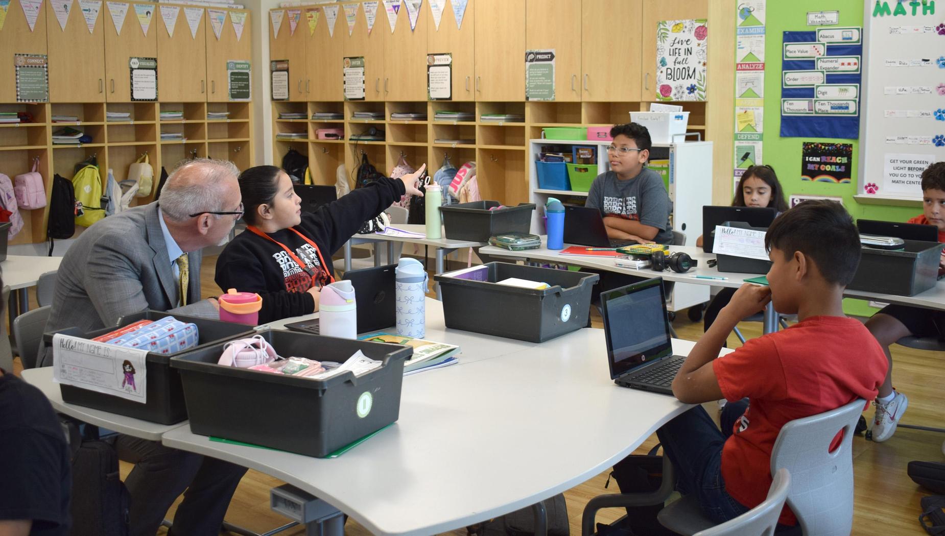 Students engaged in a classroom discussion with a teacher present.