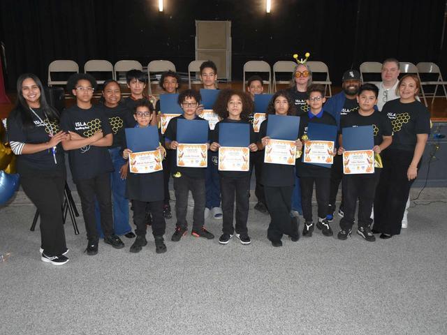 Group of students and mentors holding certificates on stage.