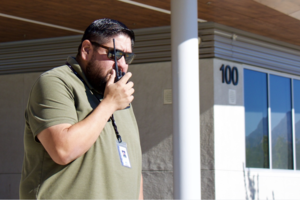 Albert Nolasco with sunglasses and a beard talks into a radio outside.
