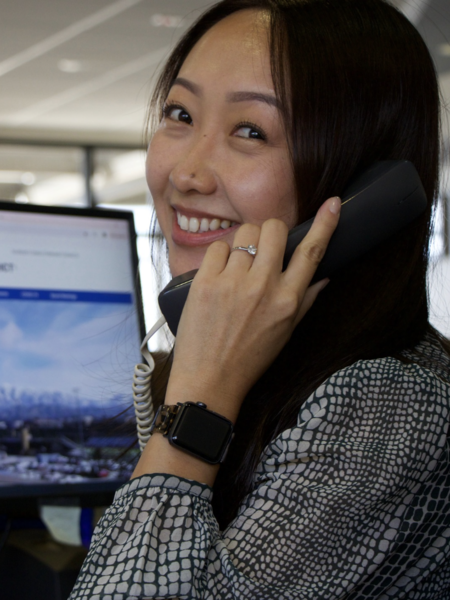 A middle age Asian woman on the phone in front of a computer