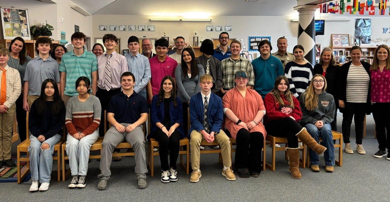 Group of students and adults posing together in a library setting.