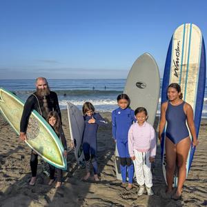 Group of students and an instructor with their surfboards