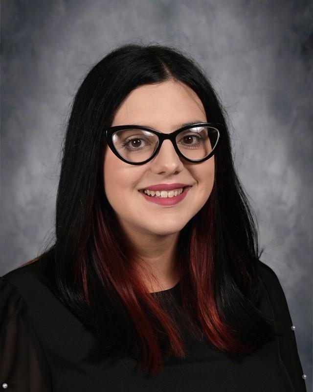 Young woman with dark hair and glasses smiling at the camera.