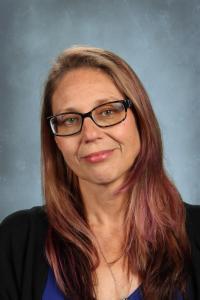 Woman with medium-length hair and glasses, wearing a dark sweater.