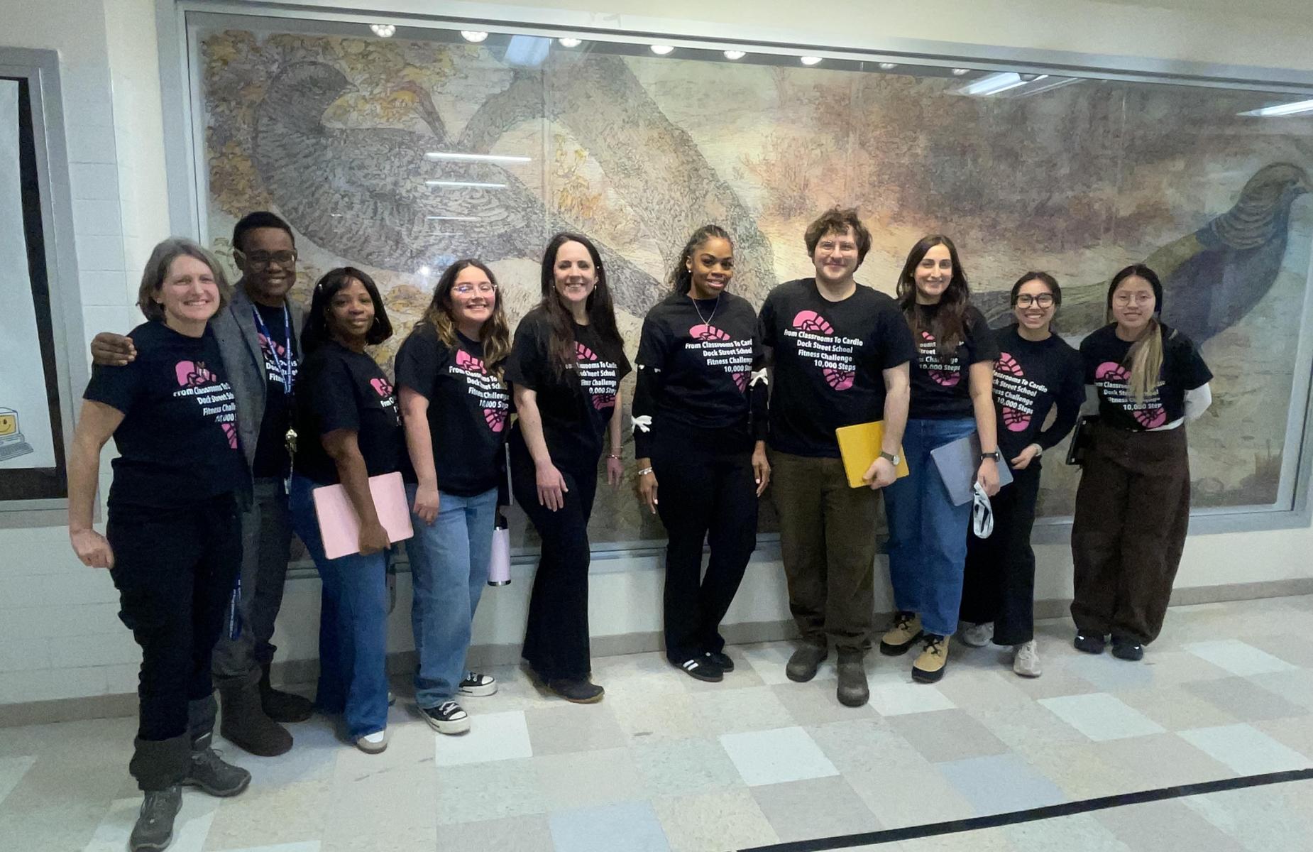 Group of people in matching shirts posing in front of a mural.