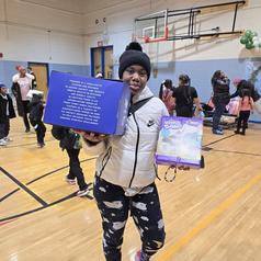 A person holding a box in a gym filled with people celebrating.