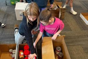 Clara Suchy and Phoebe Carneim work together to unpack donations