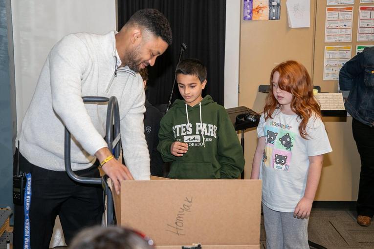 A group of three people, including two children, looking at a box during an event.