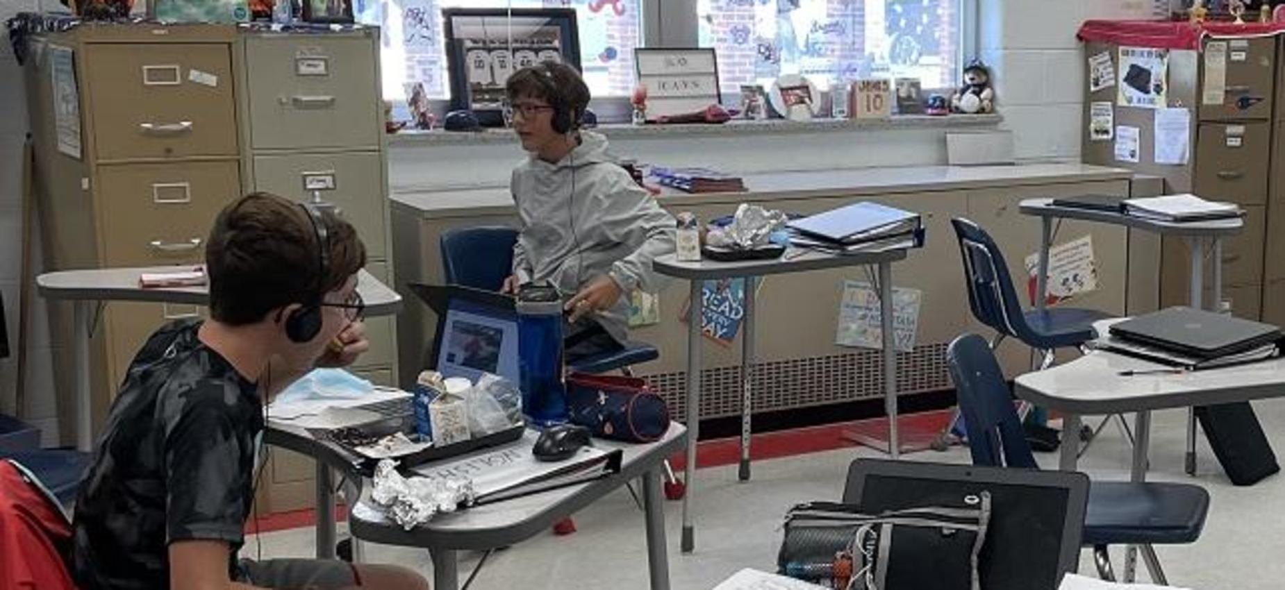 Two students work on Chromebooks in a classroom.