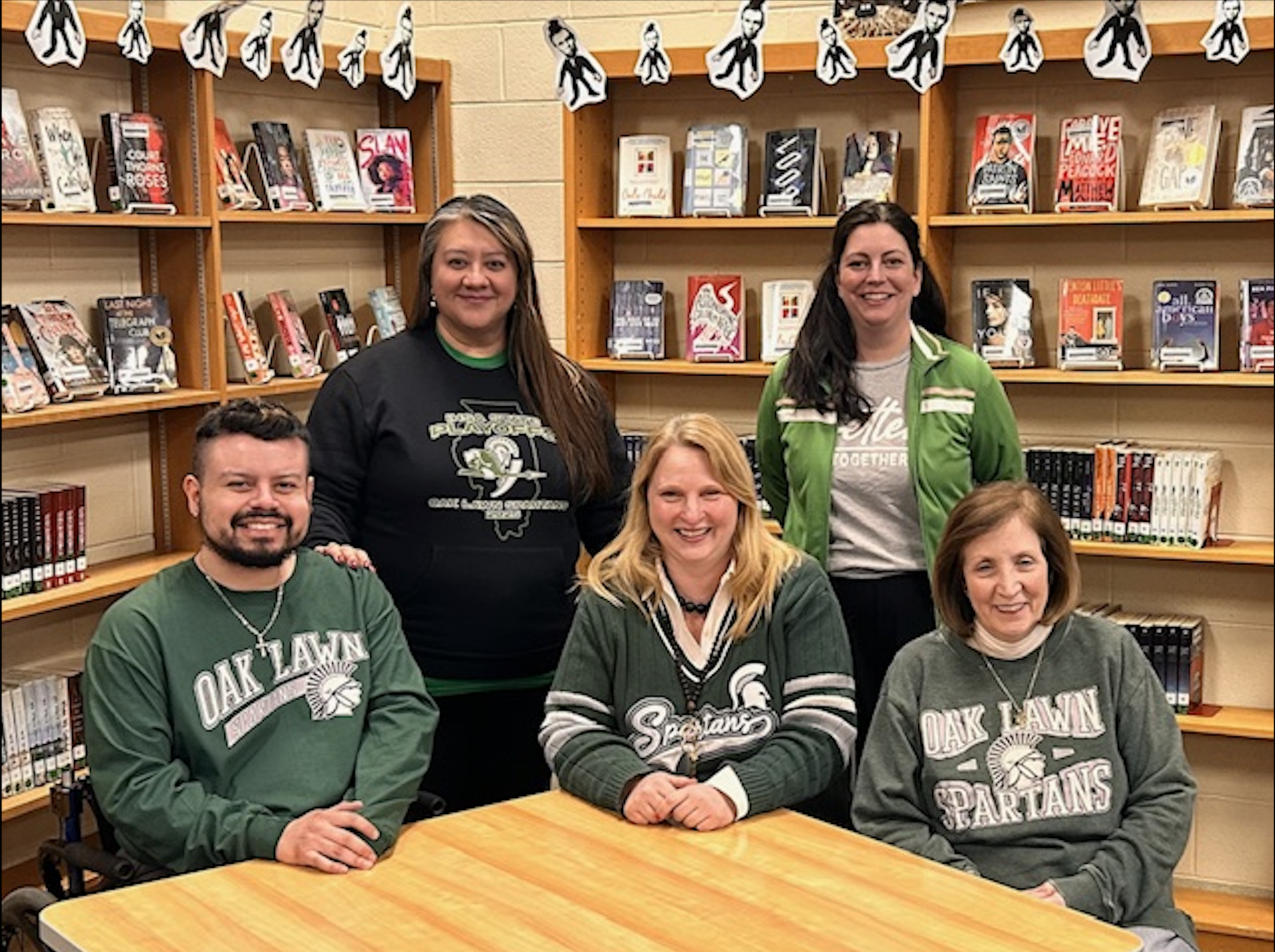 5 People posing in front of book shelfs