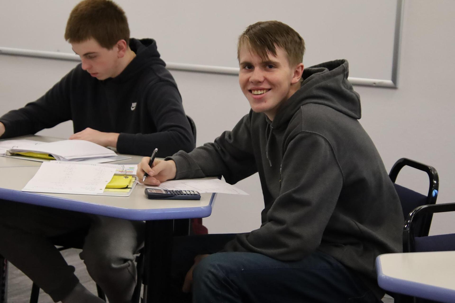 high school boy smiling for the camera in a classroom